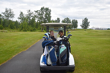 Young women enjoying golf in a cart, smiling on a lush course under a partly cloudy sky.