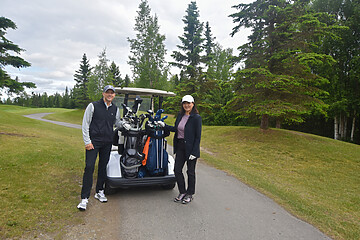 Golfers enjoying a sunny day on a lush golf course with clubs and a cart.