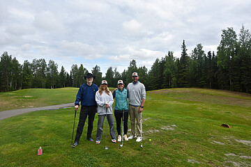 Friends enjoying a fun golf outing on a beautiful course with clubs and smiles.