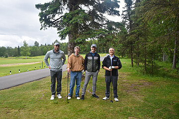 Cheerful friends enjoying a day at the golf course, dressed casually with golf clubs in hand.