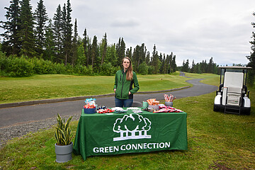 Woman engages visitors at Green Connection event in a lush, natural setting.