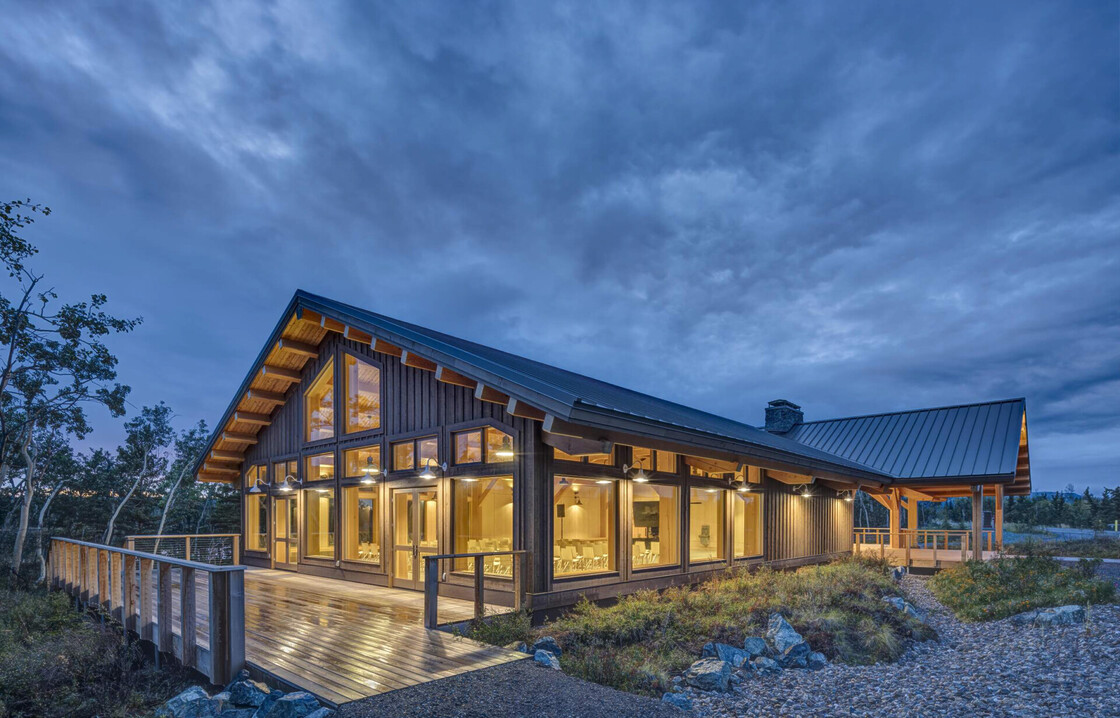 Modern cabin at twilight against a stunning sky, showcasing natural materials and serene surroundings.