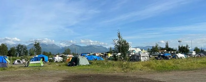 Vibrant tent encampment in mountains, showcasing community and resilience against a beautiful landscape.