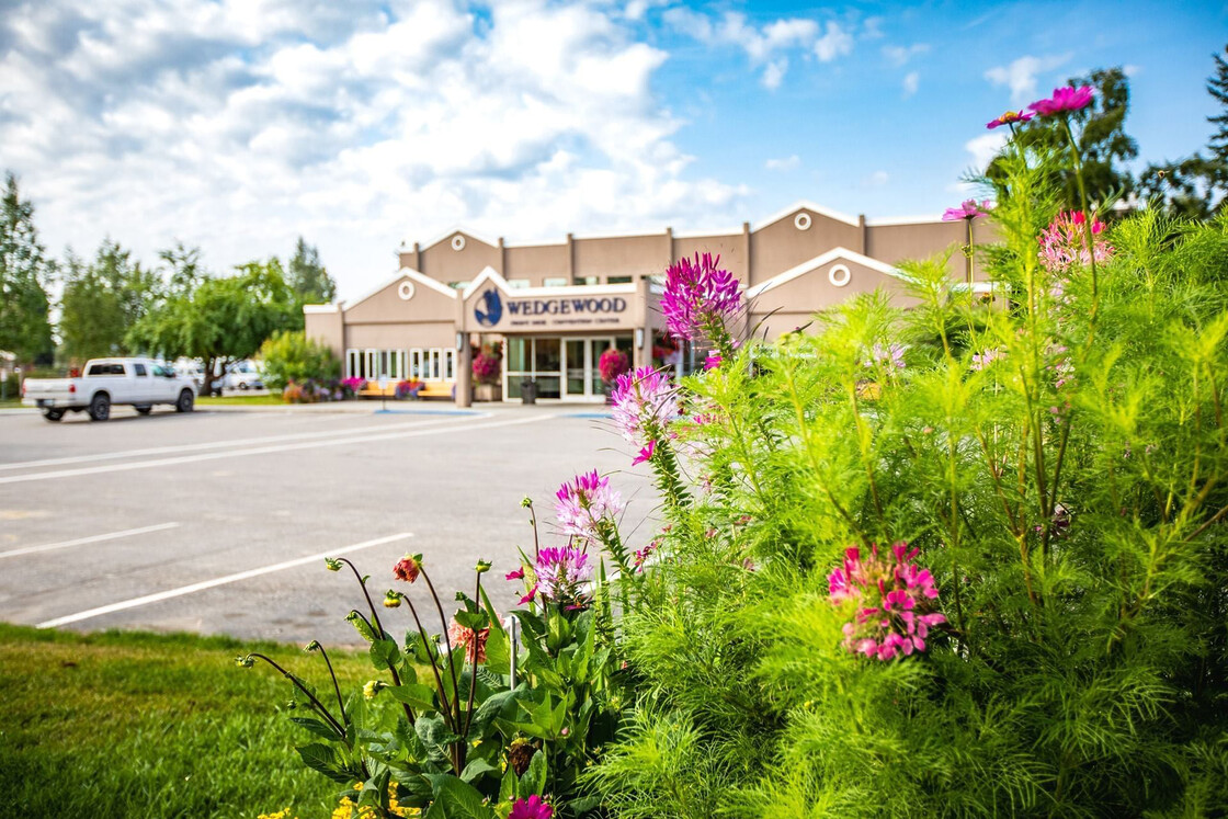 Wedgewood Community Center surrounded by vibrant gardens and inviting architecture on a sunny day.